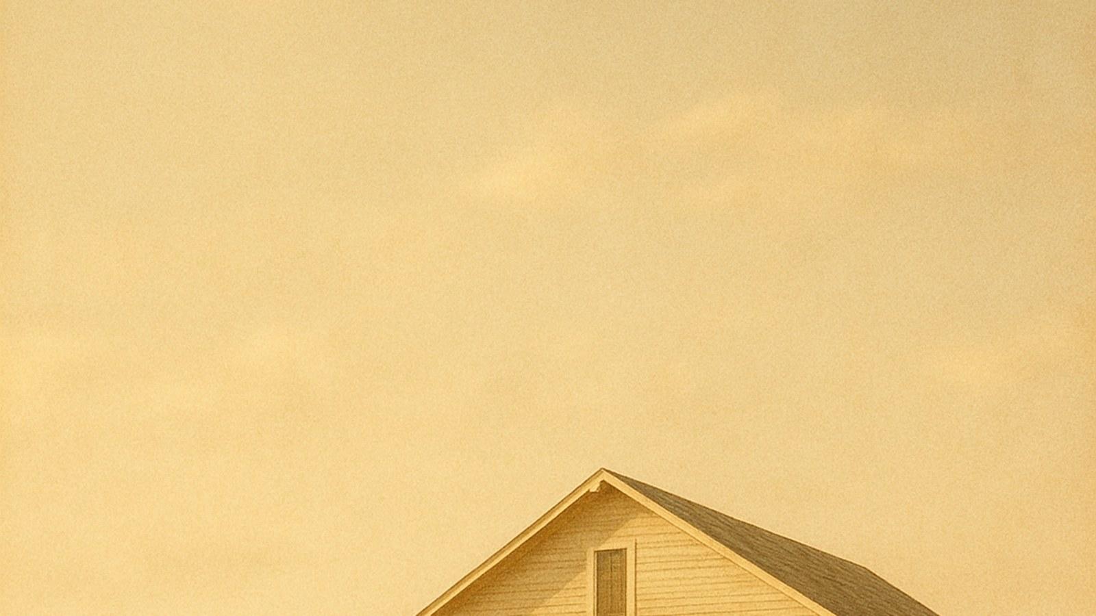 A modest two-story wooden hotel on the empty sand of early Miami Beach, warm golden light