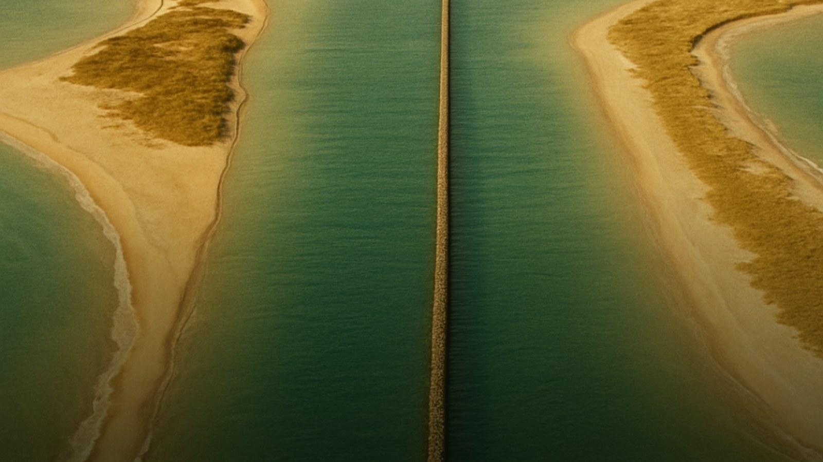 Aerial hand tinted postcard view of a shipping channel cut between two golden sand islands