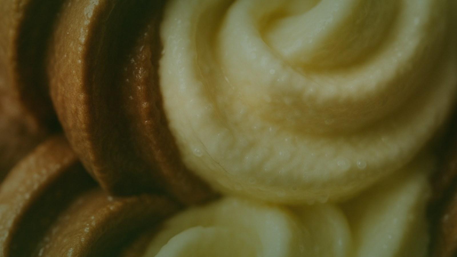 An ice cream pint and spoon on a warm neutral surface
