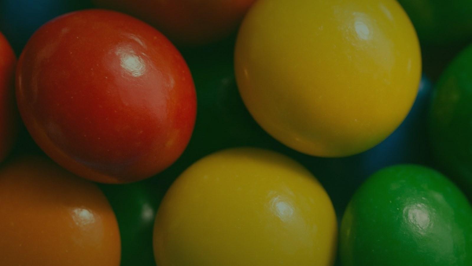 Colorful candy-shelled chocolates in a small bowl on a warm surface