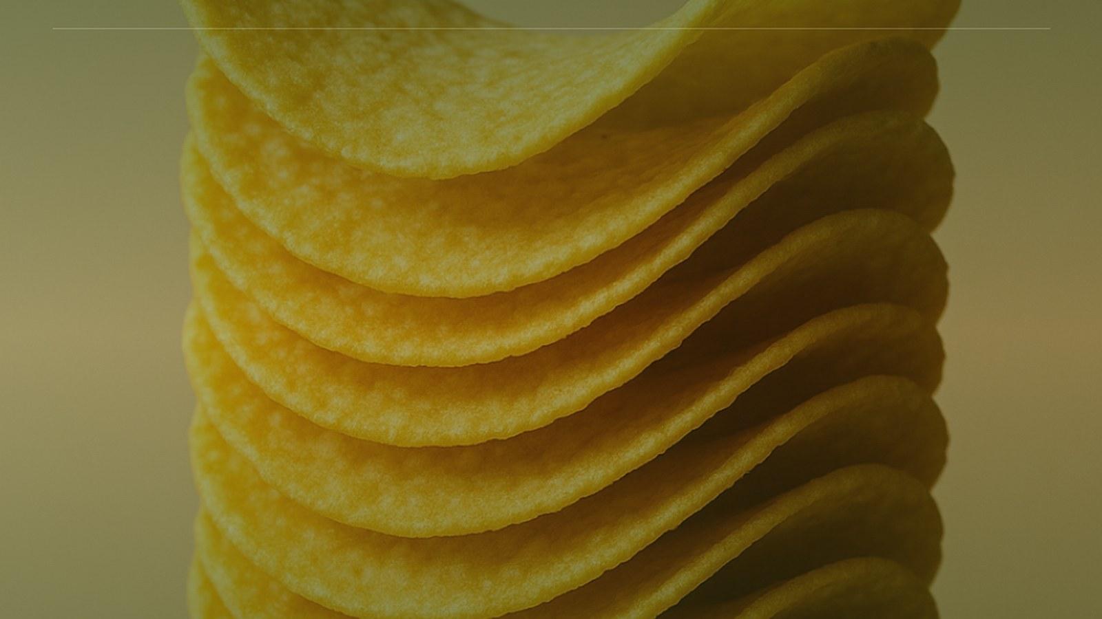 A Pringles can and stacked crisps on a warm neutral surface